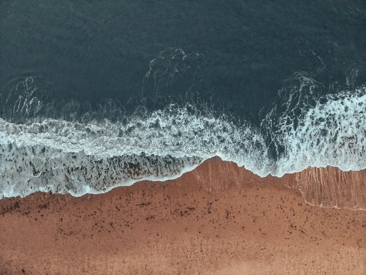 an image of a sandy beach with waves coming towards the shore