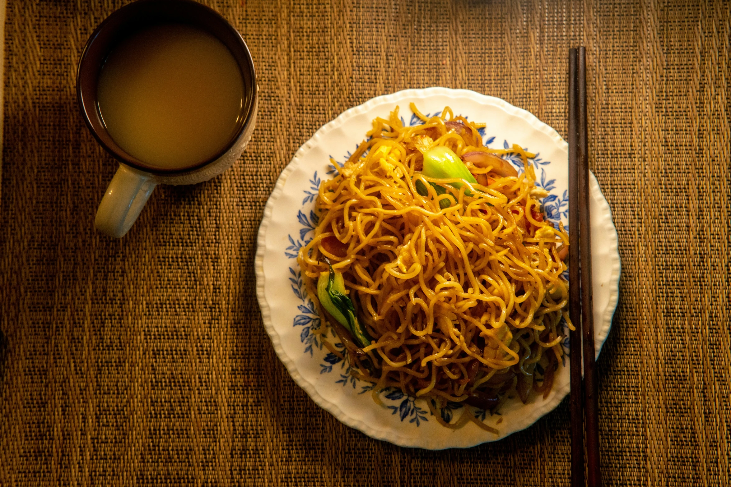 a plate full of noodles and soup with some chopsticks next to it