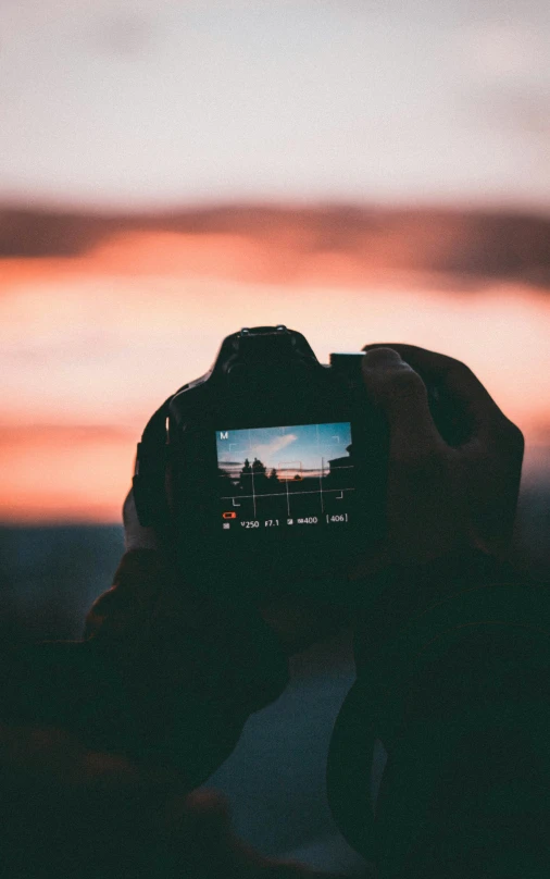 a person taking pictures at sunset with their camera