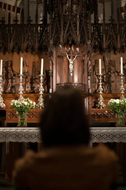 a lady sitting alone in front of some candles and flowers