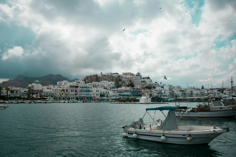 two boats moored along the edge of the water with a city skyline on the other side