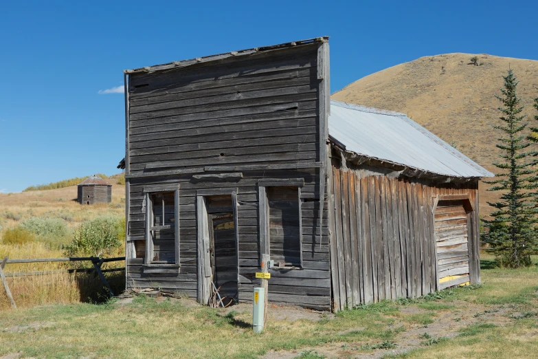 an old, run down building near a field and mountains