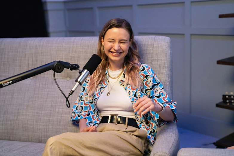 a woman is sitting down near a microphone smiling