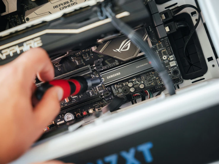 a person working on an electronic device underneath the motherboard