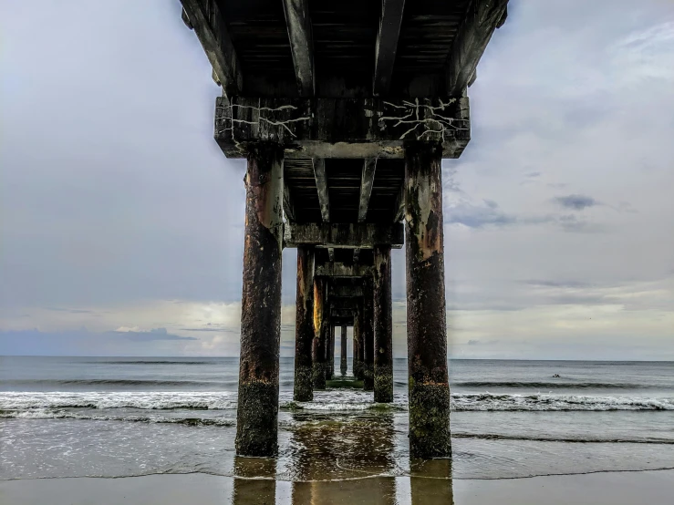 looking out into the ocean underneath an abandoned pier