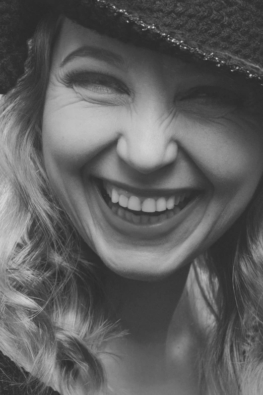 smiling young woman in black and white with long hair and large hat