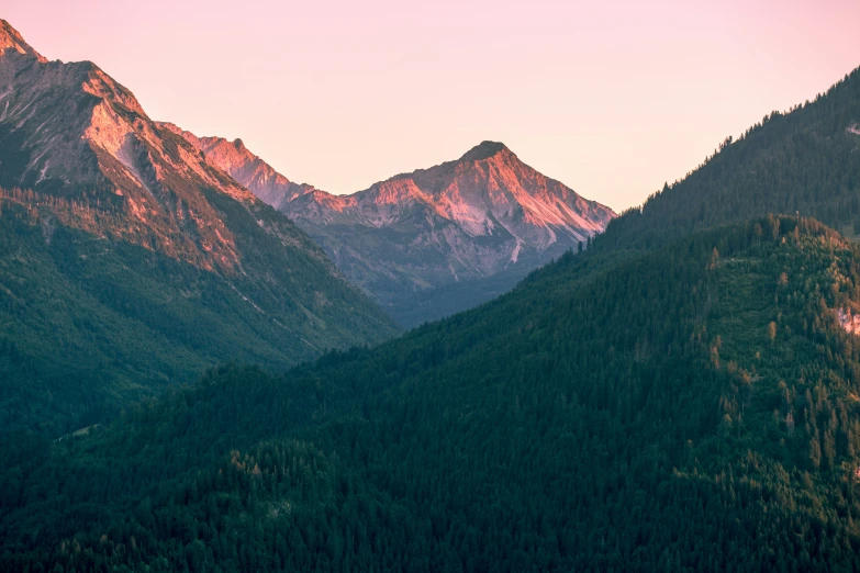 several hills and trees with mountains in the background