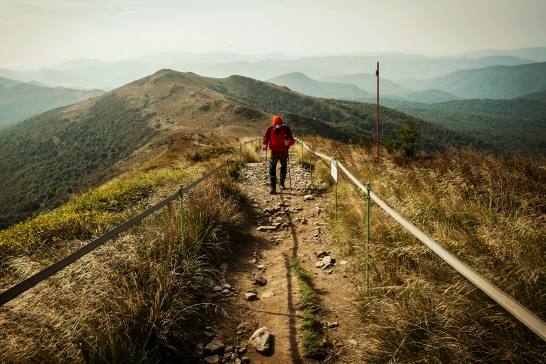 a man walking down a dirt trail up a hill