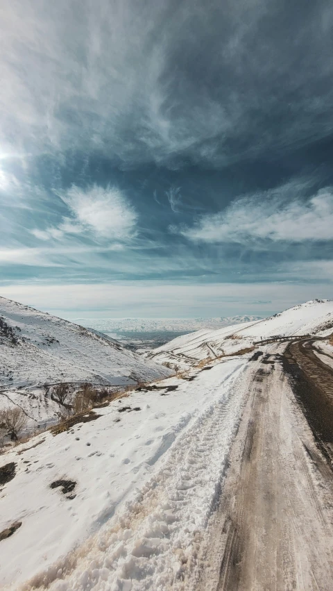 a snow covered road with a very dark cloud filled sky