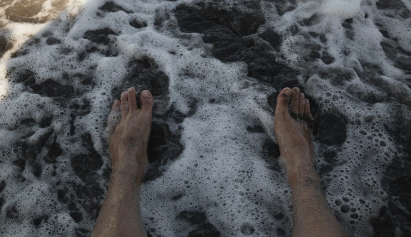 the view of a man standing in the foamy ocean