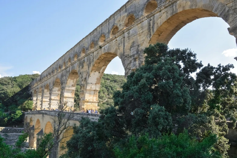 a train crosses an old stone bridge over trees