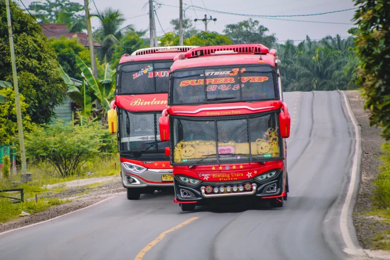 two red buses driving next to each other on the street