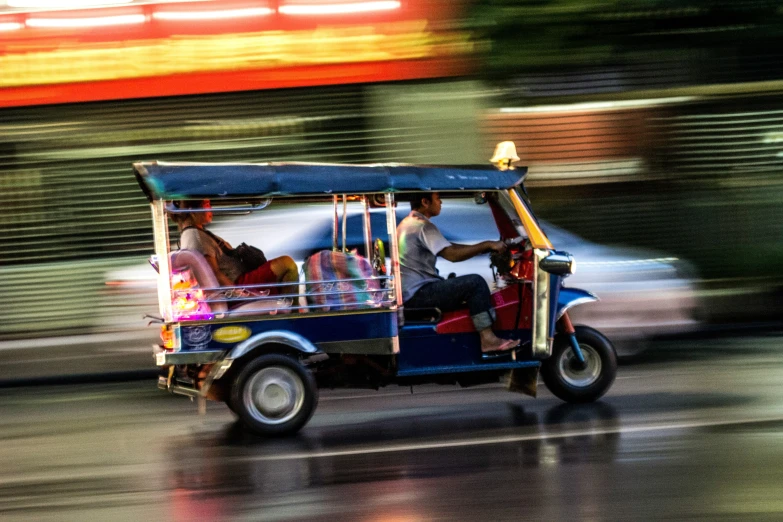 people riding in a small cart on a wet road