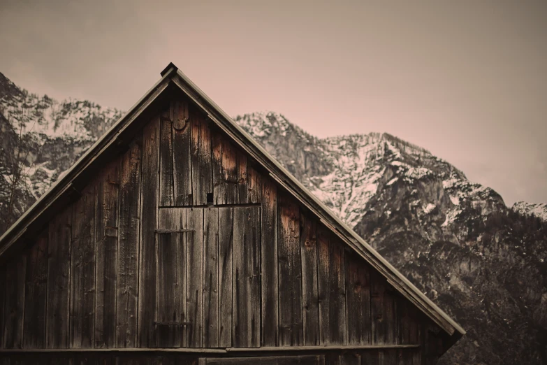 a rustic wooden barn sitting below a mountain range