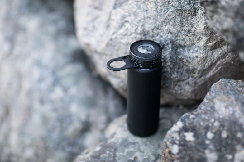 a black flask sitting on a rock in the sun