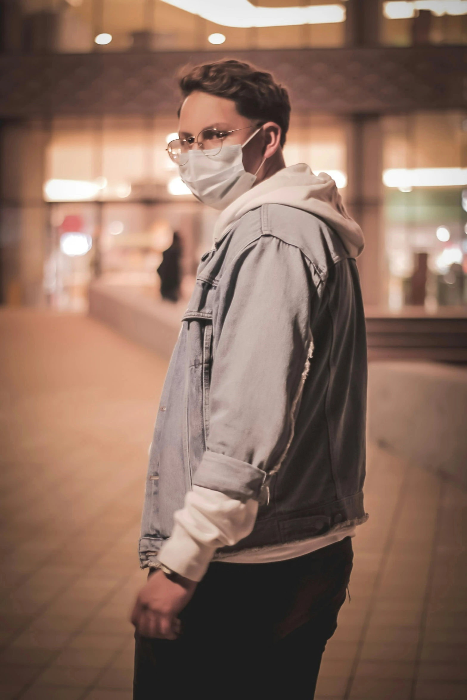 a man wearing a face mask stands on the sidewalk