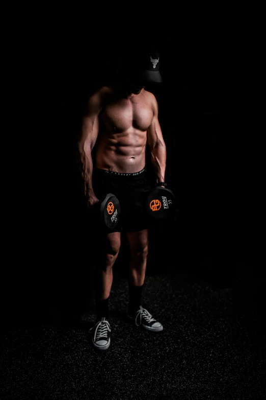 shirtless man standing in the dark wearing a pair of shorts