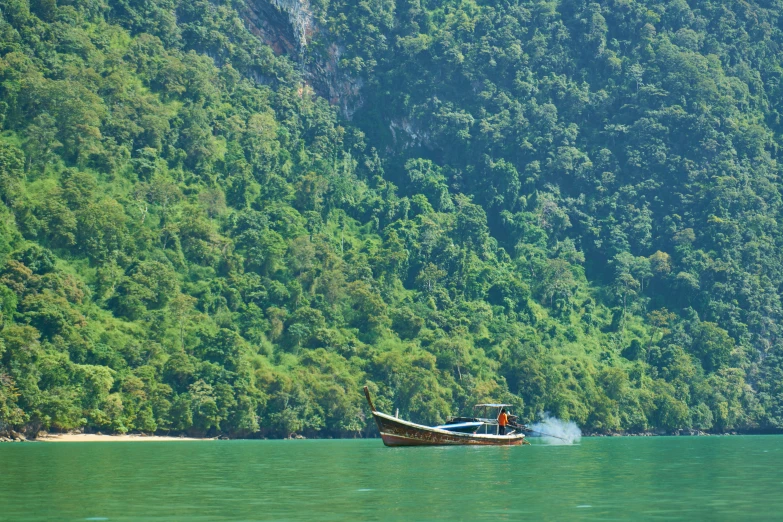 a lone boat floats in front of a mountain