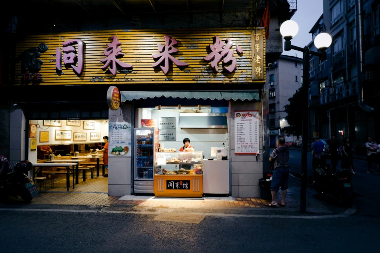 a restaurant with chinese writing at night with people