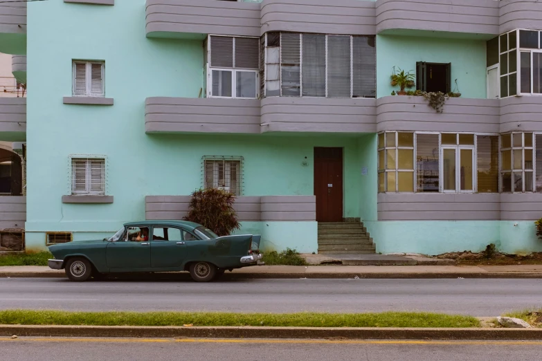 a green car parked in front of an apartment building