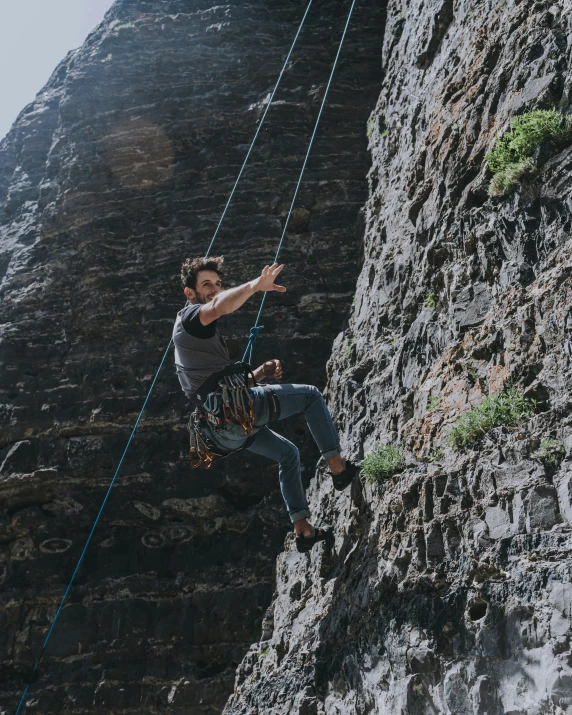 a male climber on a rope is on top of a mountain