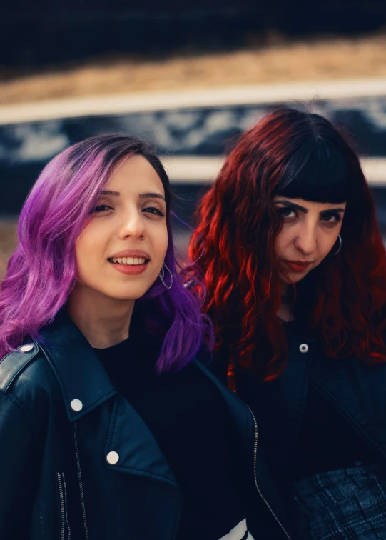 two beautiful women wearing purple hair in front of an artistic wall