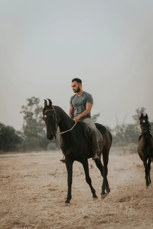 a man riding a horse around a field in front of another