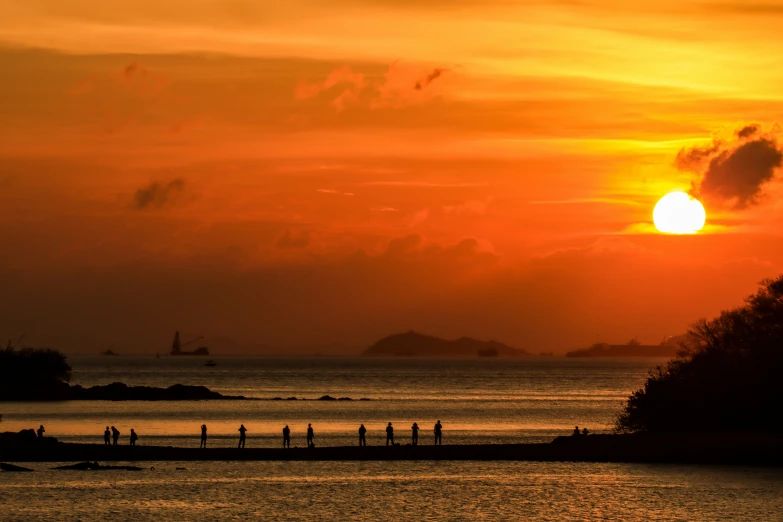 two people walking on beach and water near shore at sunset