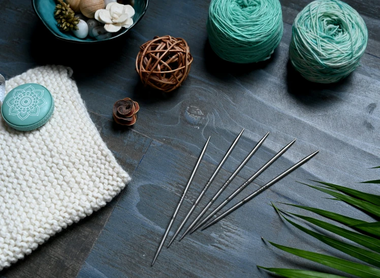 a basket of yarn, needles and knitting needles