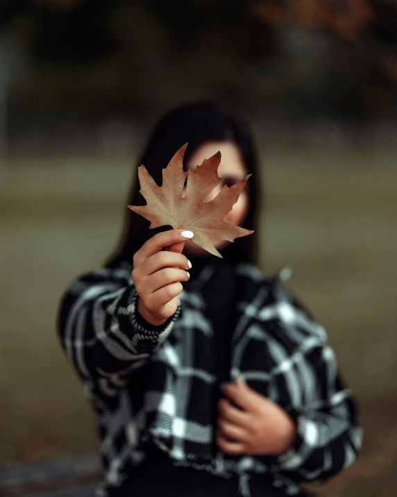 woman with maple leaf close up to face