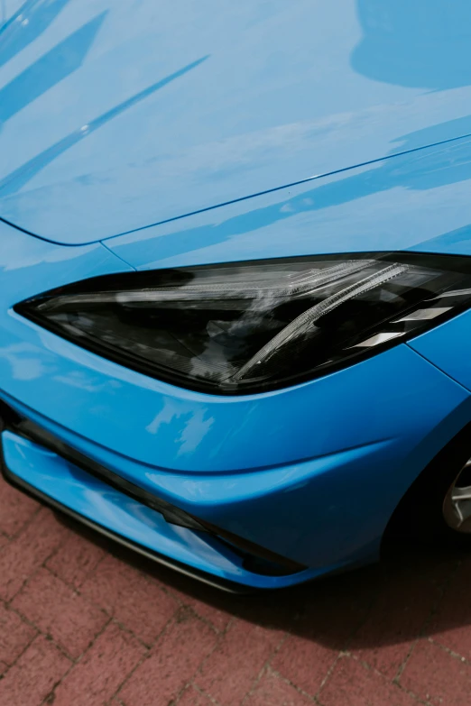 a blue sports car on the street with its hood partially opened