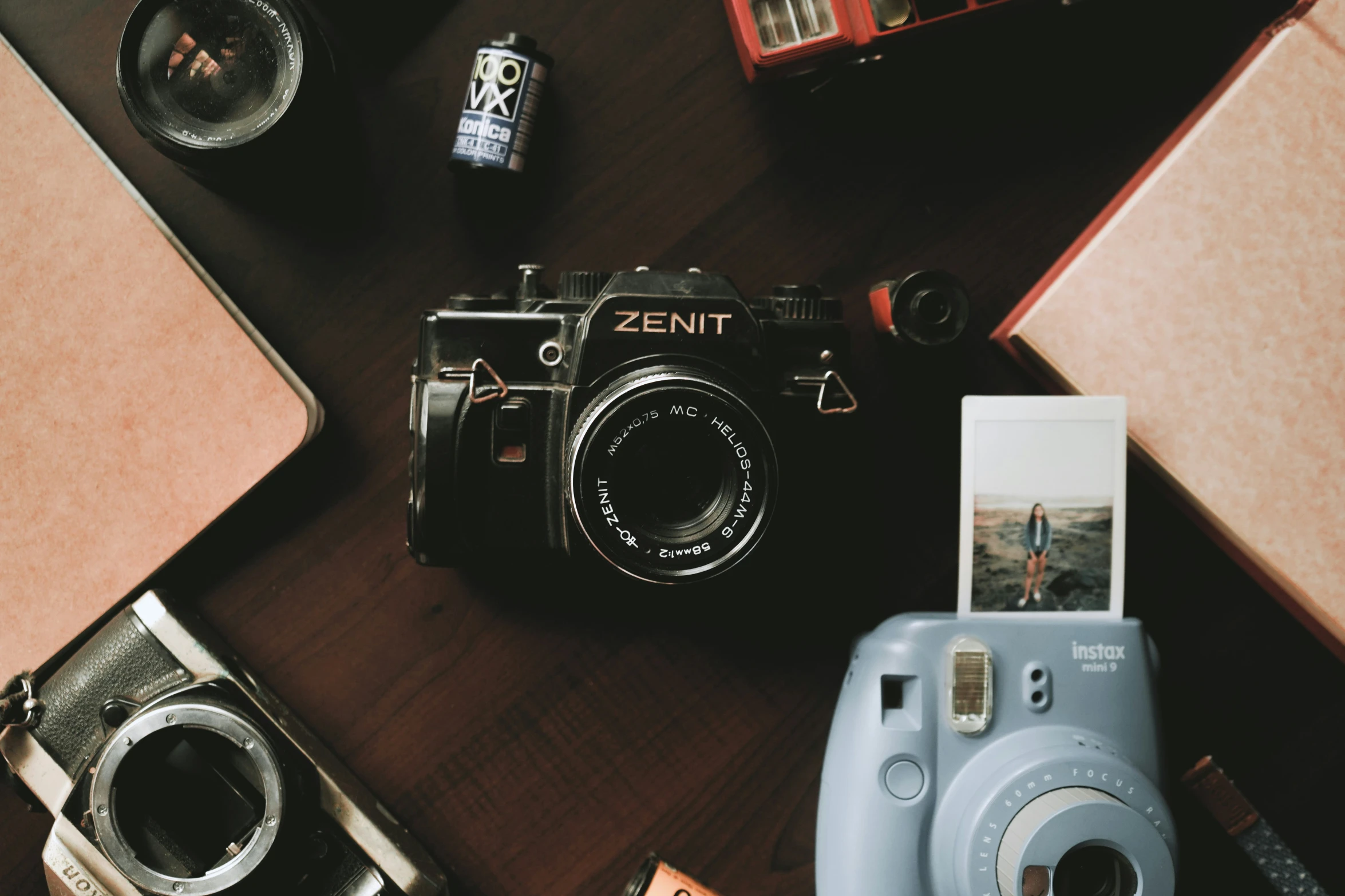 an old and new camera on a table with a coffee mug