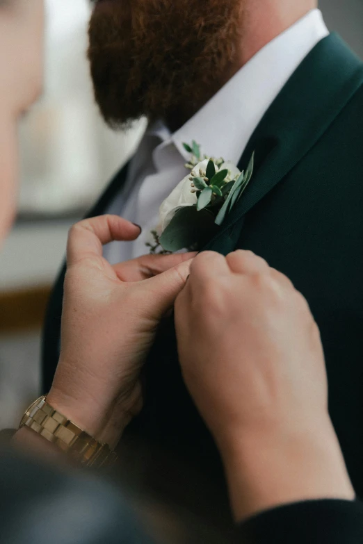 a person adjusts his jacket with a boutonniere