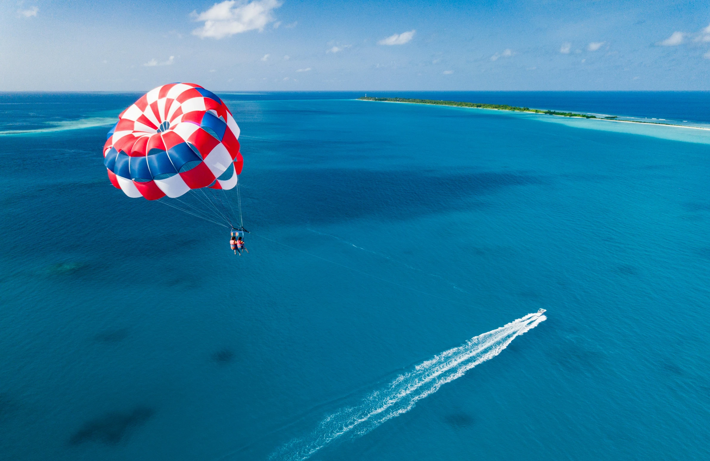 an aerial view of an ocean with two people parasailing