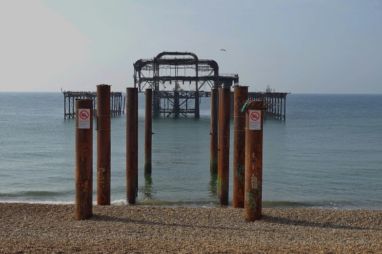 a beach with several posts sticking out from the water