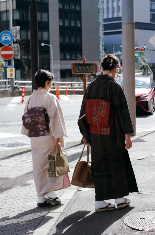 two ladies in geisha attire walking on the street