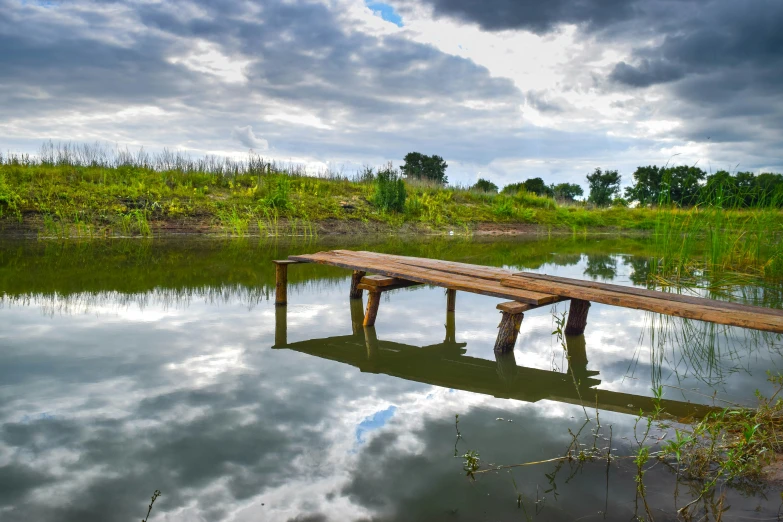 a dock sitting in the water on top of a cloudy day