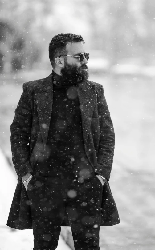 a bearded man in black overcoat walking