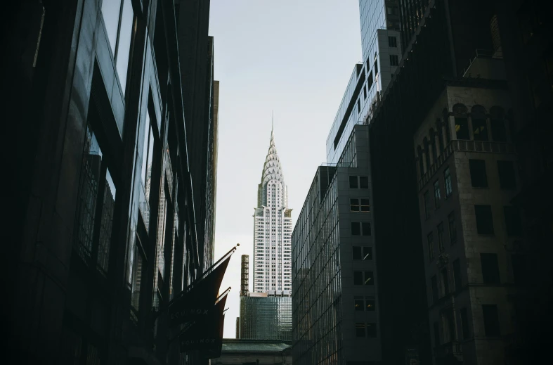 the view of a clock tower seen from behind tall buildings