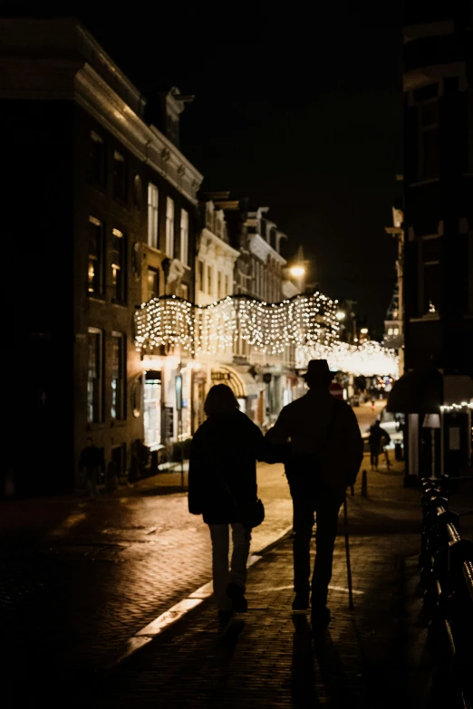 two people walk on a brick street next to some buildings