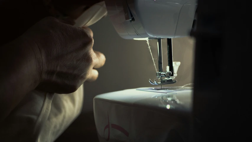 a person using a sewing machine in a dark room