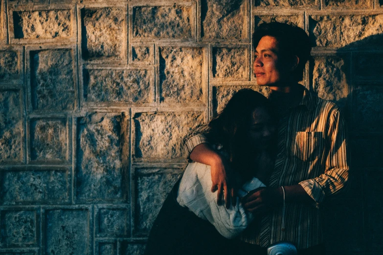 a man hugging a woman in the street next to a wall