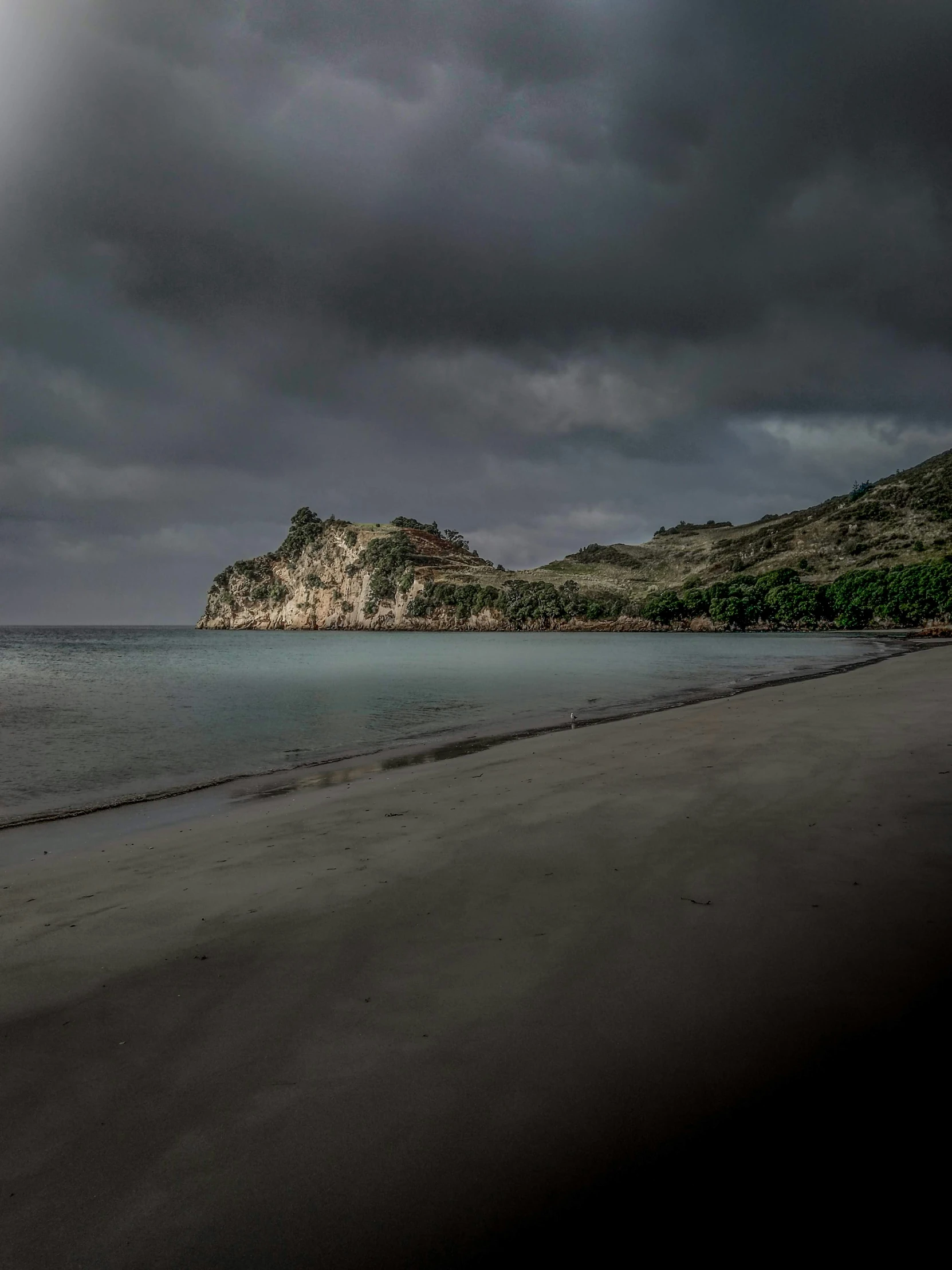 a lone beach and rocks on a dark stormy day