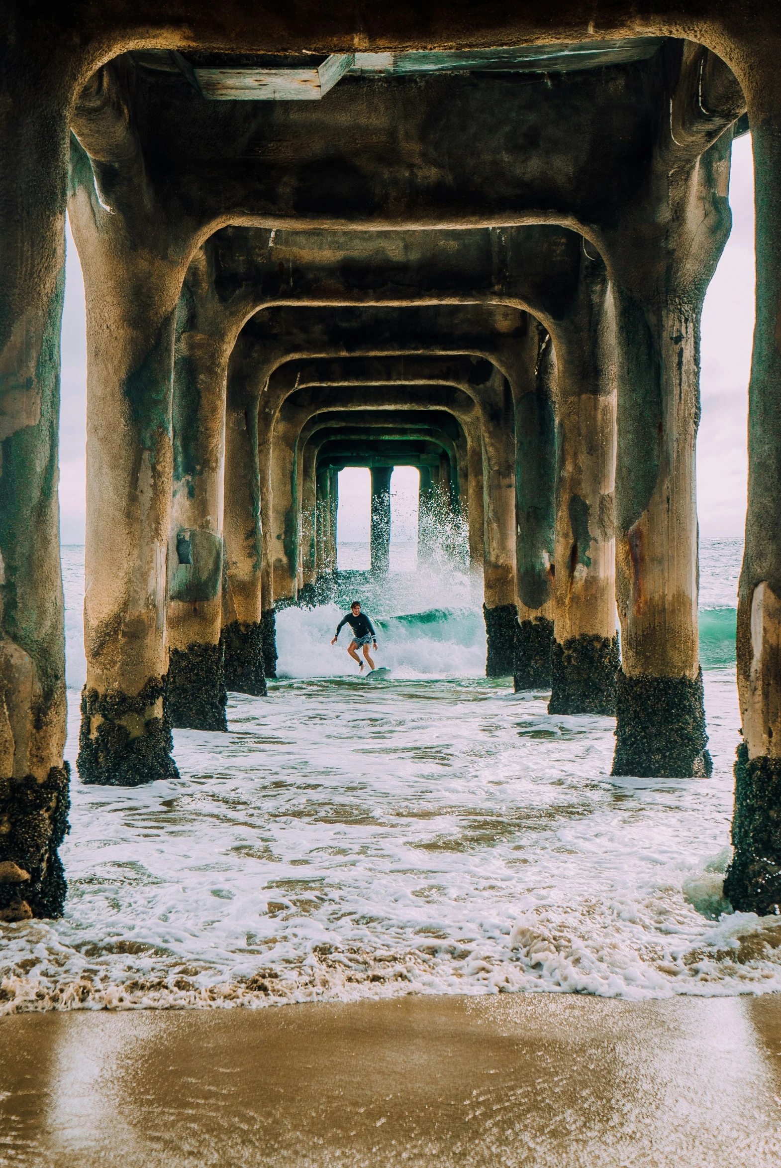 a person riding a surfboard under an arch in the sand