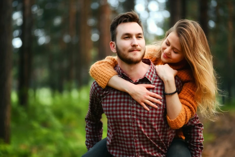 two people, a woman and man, are holding each other while walking through the woods