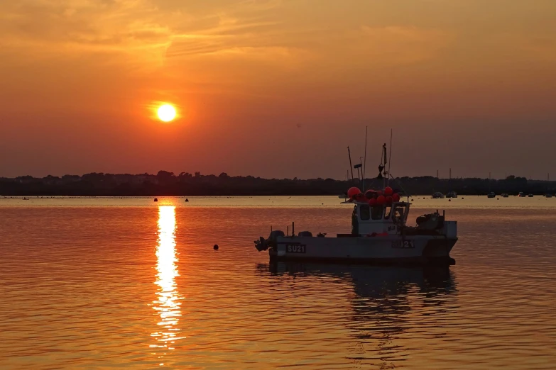 a large boat floating in the middle of a large body of water at sunset