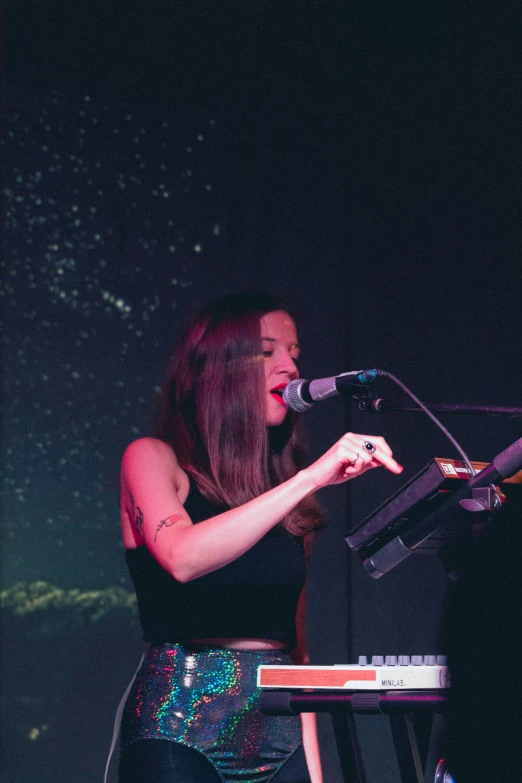 a beautiful young woman playing piano and singing on stage