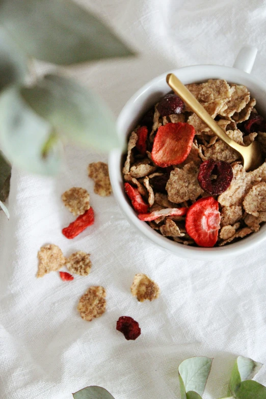 a bowl of granola and fruit with a gold spoon