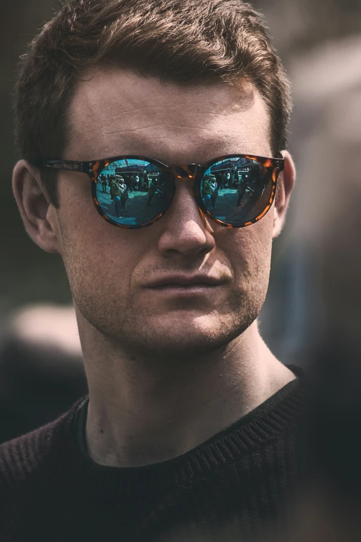 a man wearing sunglasses with blue and gold mirrored shades