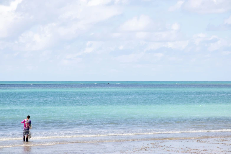 a man standing on top of a beach under a kite